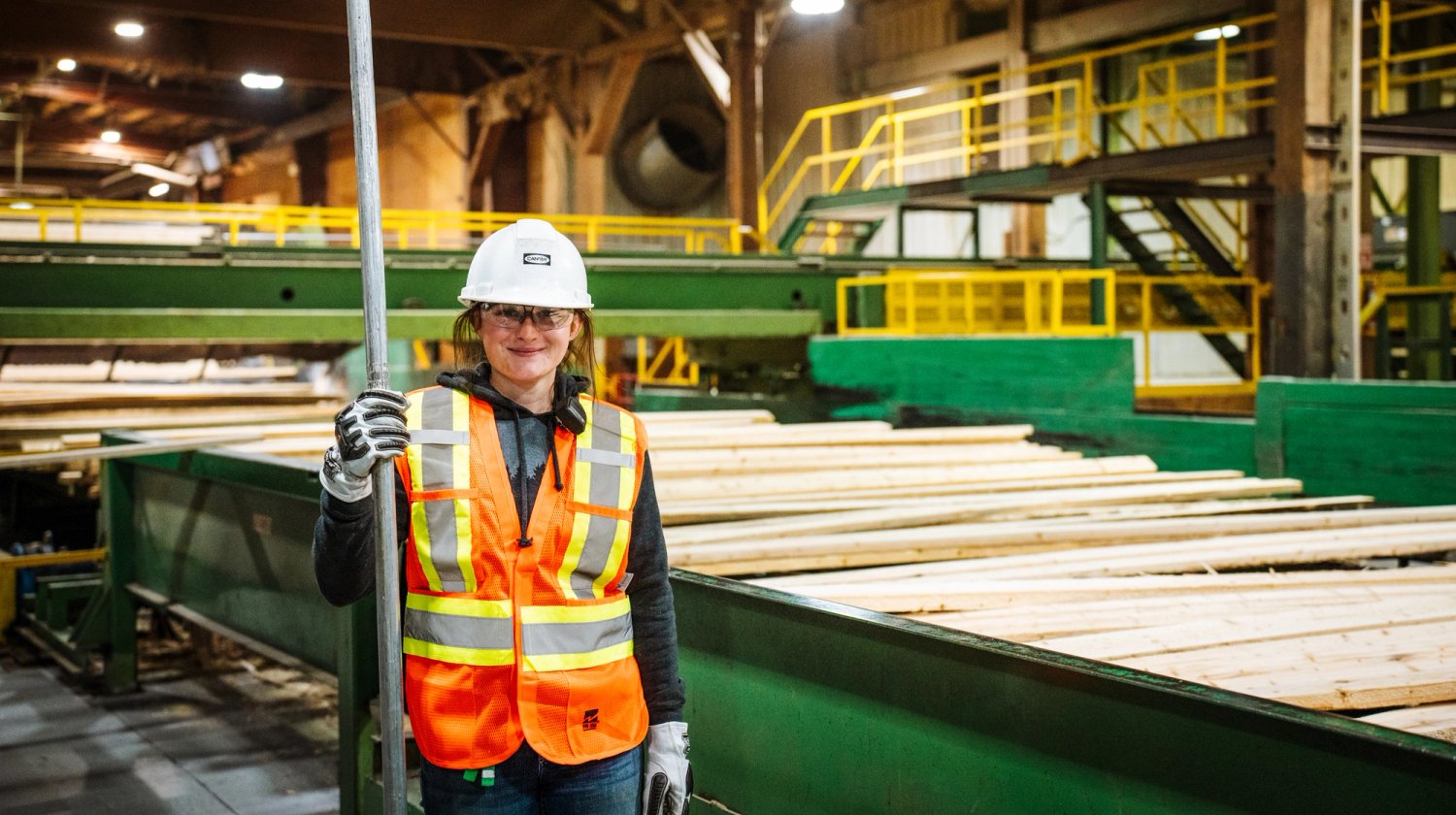 a woman is standing in a factory holding a pole .