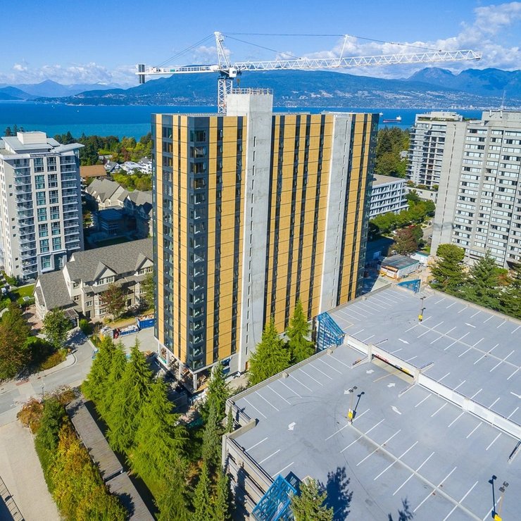 An aerial view of a tall mass timber building under construction in a city.
