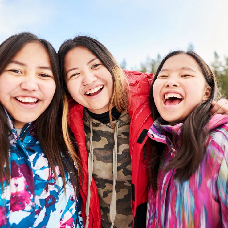 three young women are posing for a picture in the snow .
