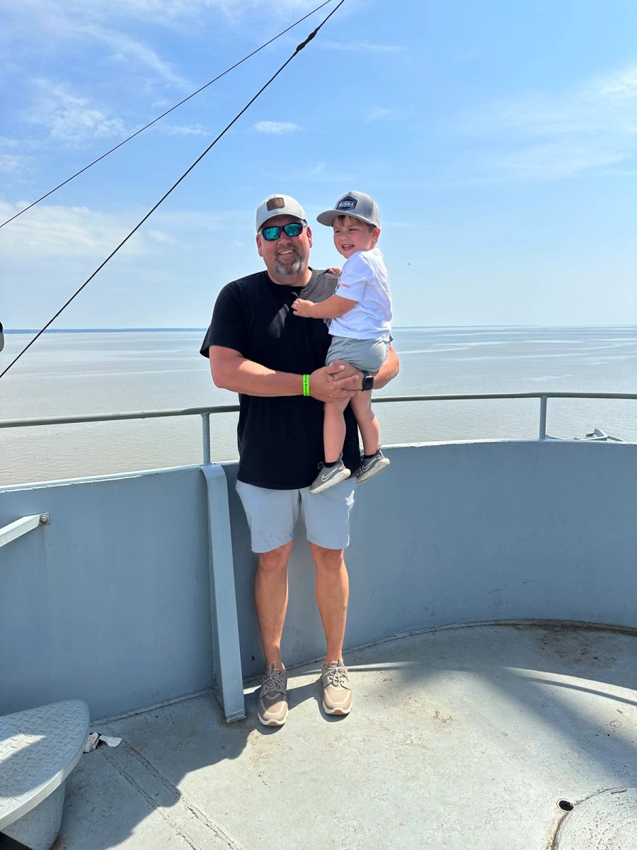 a man is holding a child on his shoulders on a boat