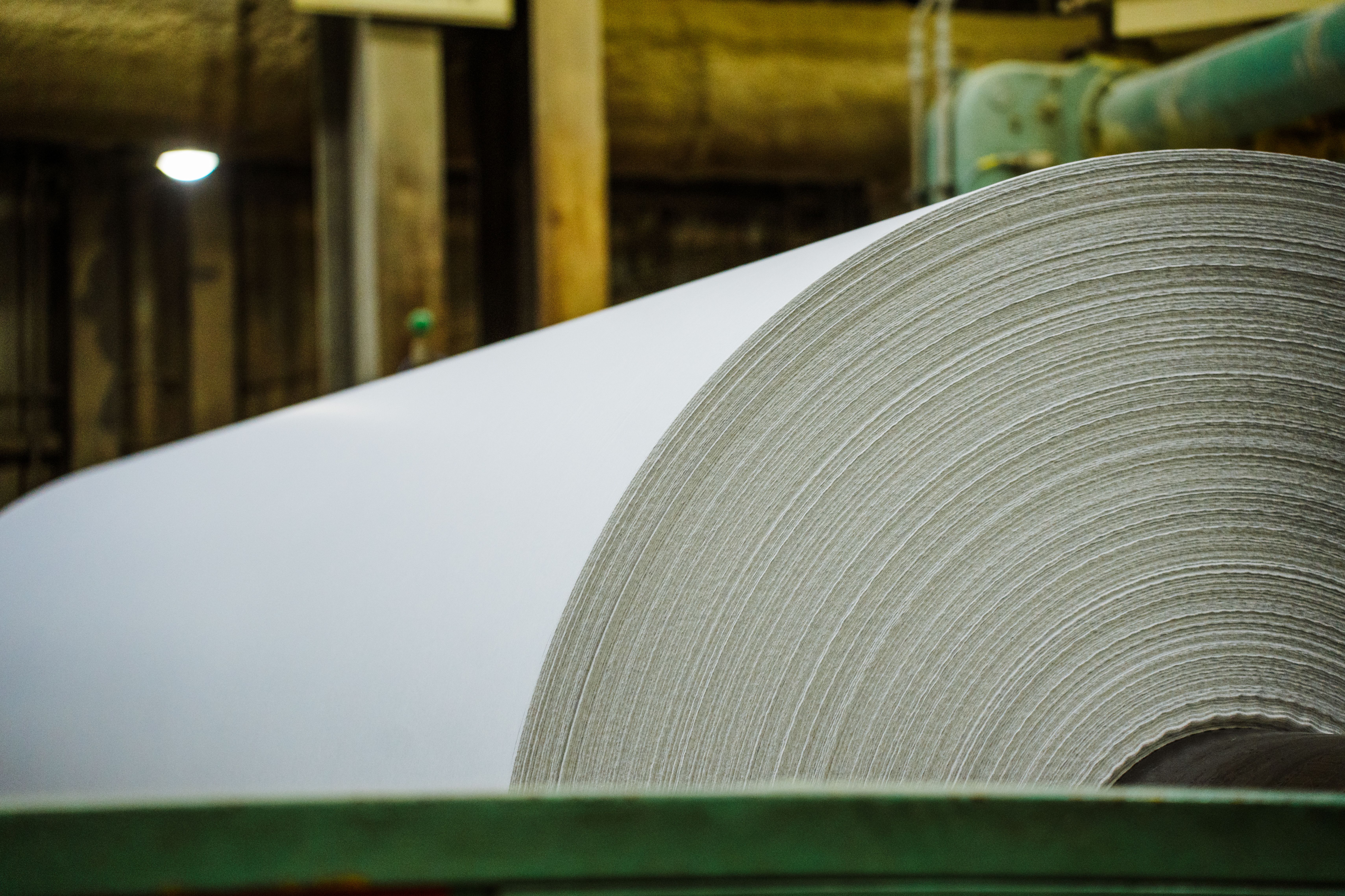 a roll of paper hangs from a lift inside a factory