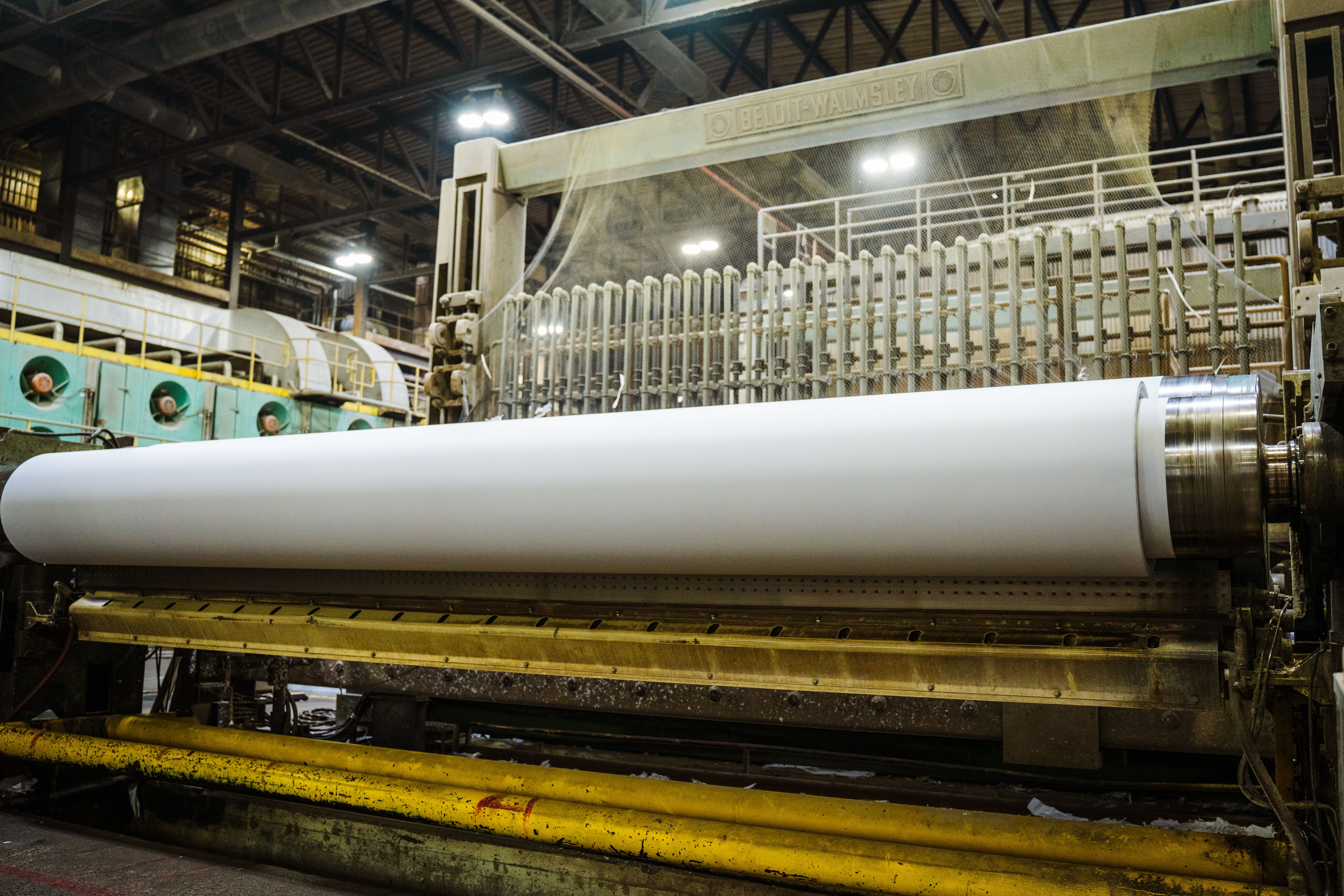 a large roll of paper is being rolled on a machine in a factory .