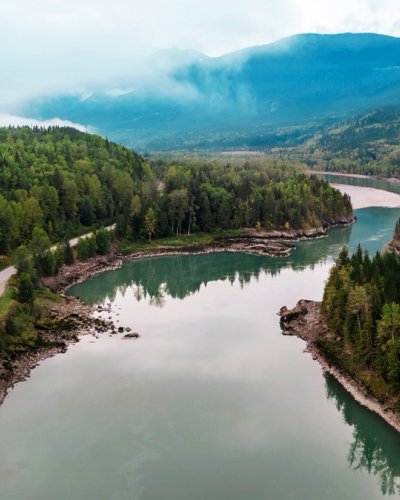 an aerial view of a river surrounded by mountains and trees .
