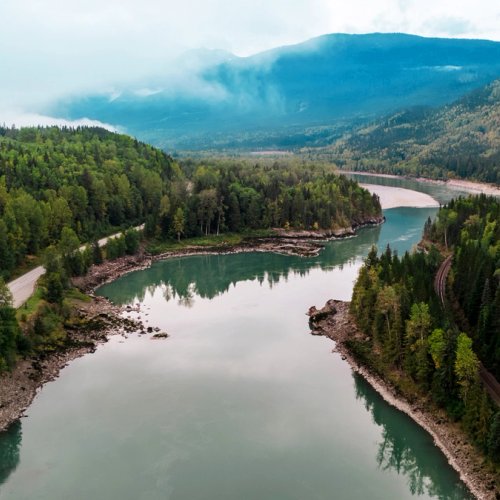 an aerial view of a river surrounded by mountains and trees .