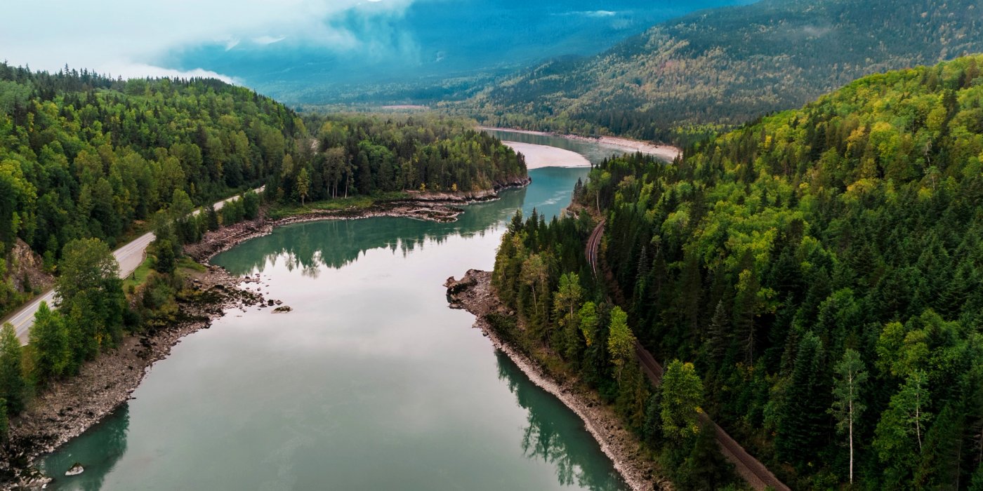 an aerial view of a river surrounded by mountains and trees .