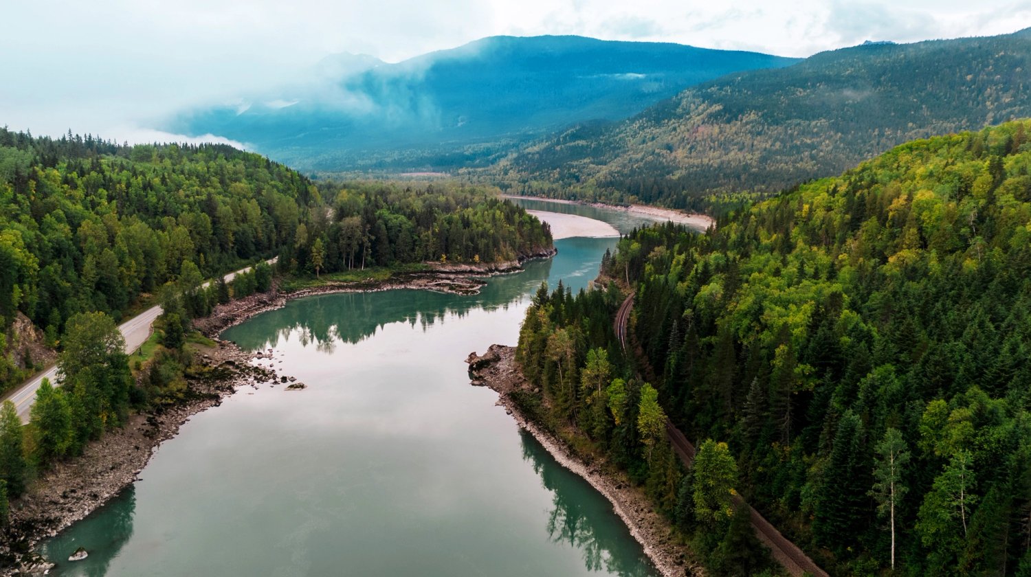 An aerial view of the Skeena River in British Columbia, surrounded by mountains and trees.