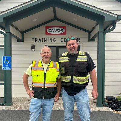two men standing in front of a canfor training center