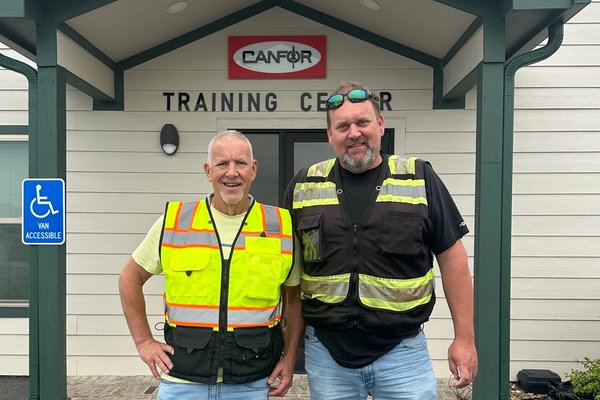 two men standing in front of a canfor training center