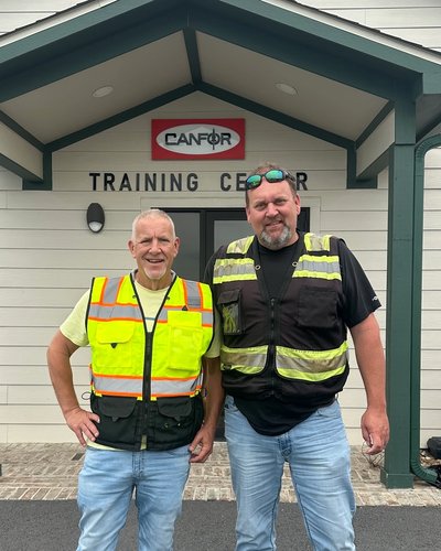 two men standing in front of a canfor training center