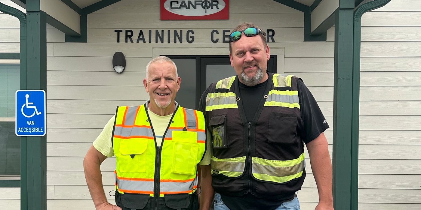 two men standing in front of a canfor training center
