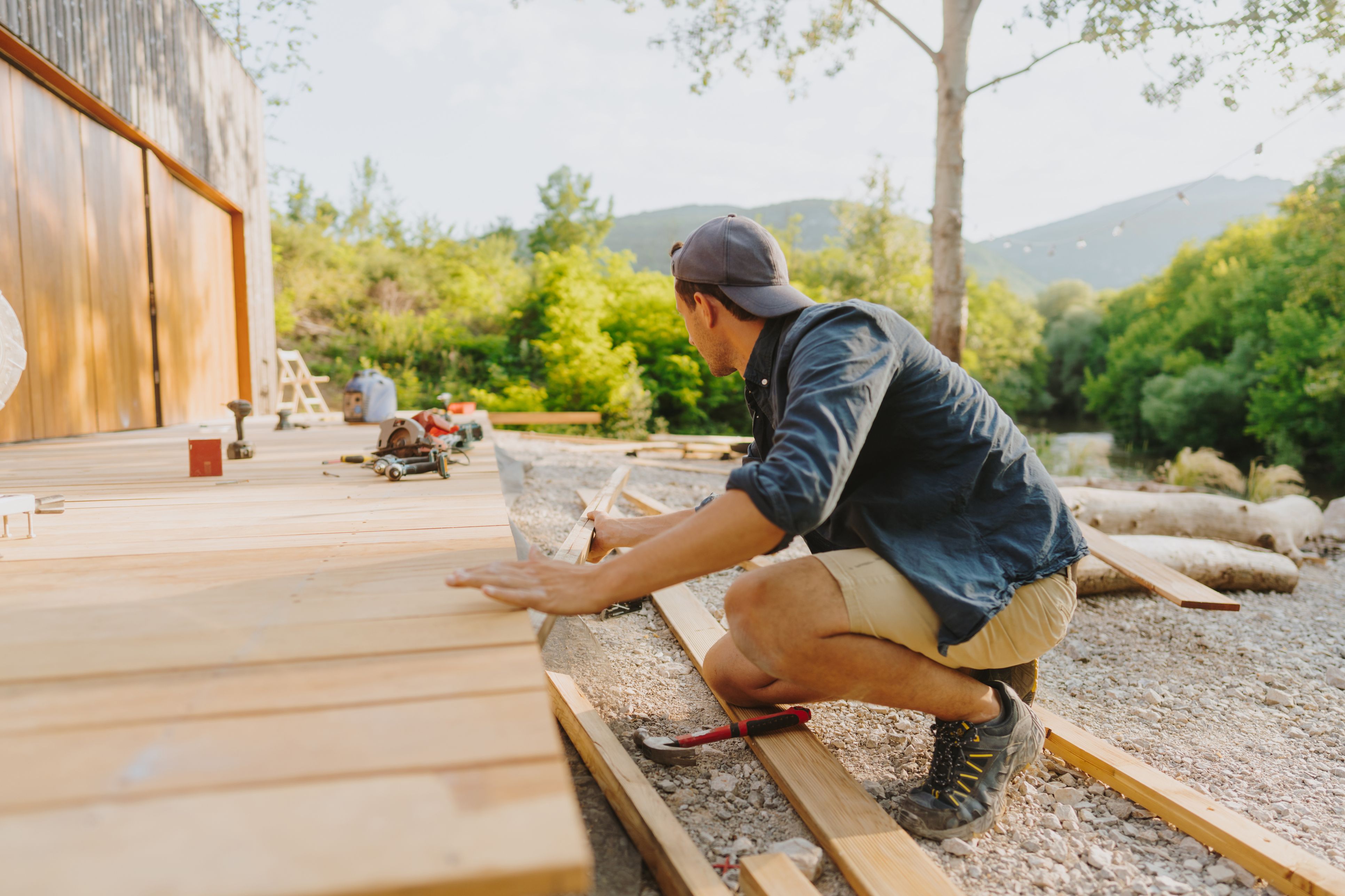 Man building a wooden deck outdoors.