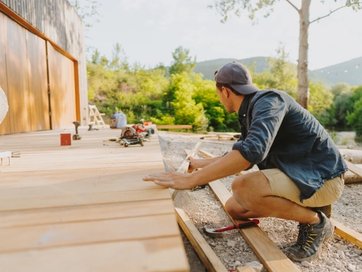 Man building a wooden deck outdoors.
