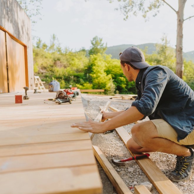 Man building a wooden deck outdoors.