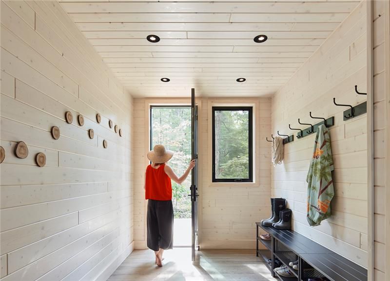 a woman is walking through a hallway in a wooden house.