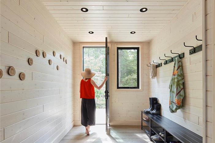 a woman is walking through a hallway in a wooden house.