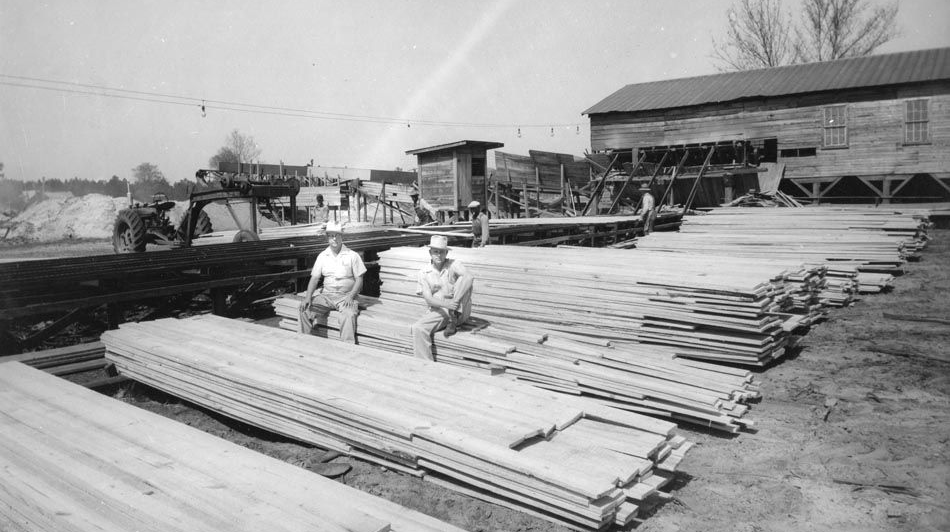 Old photo of two people sitting on lumber