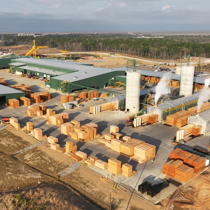 An aerial view of a sawmill with a large log pile in the middle.