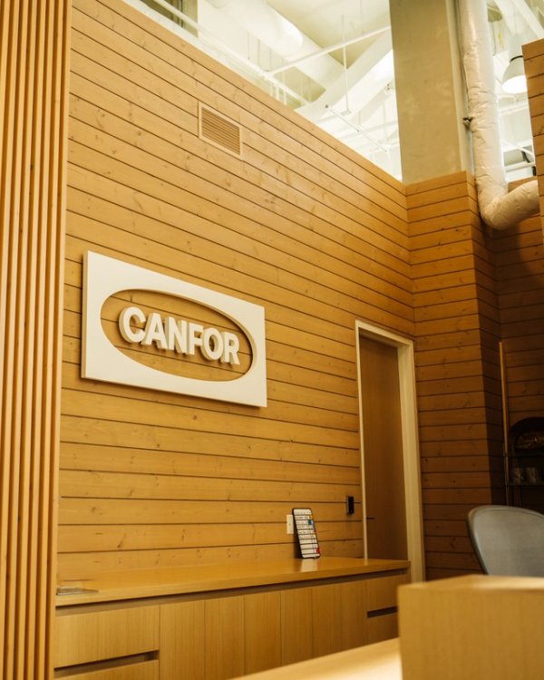 a wooden wall with a Canfor logo sign on it.