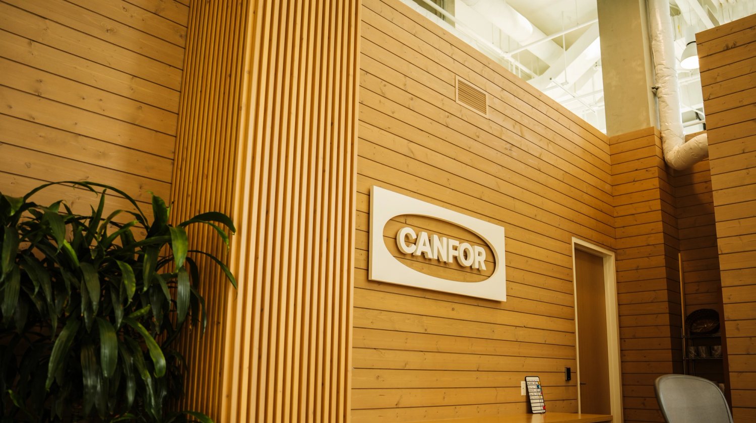a wooden wall with a Canfor logo sign on it.
