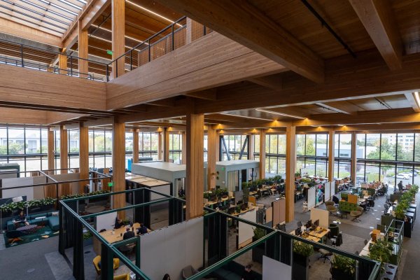 a large wooden building with lots of windows and people working in it .