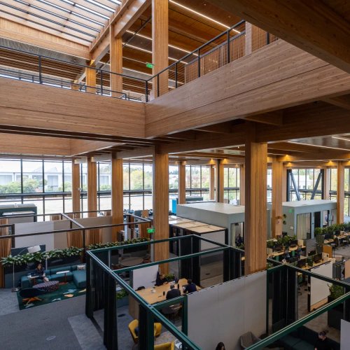 a large wooden building with lots of windows and people working in it .