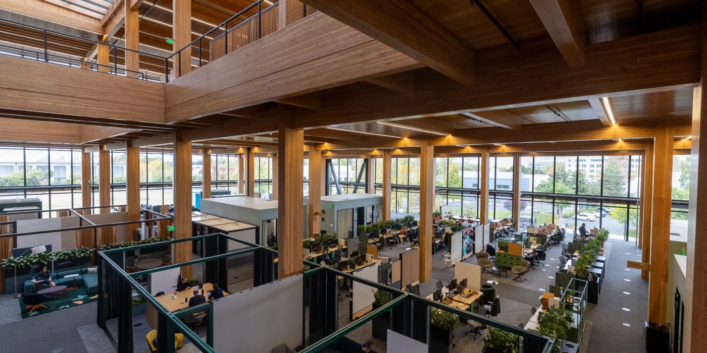 a large wooden building with lots of windows and people working in it .
