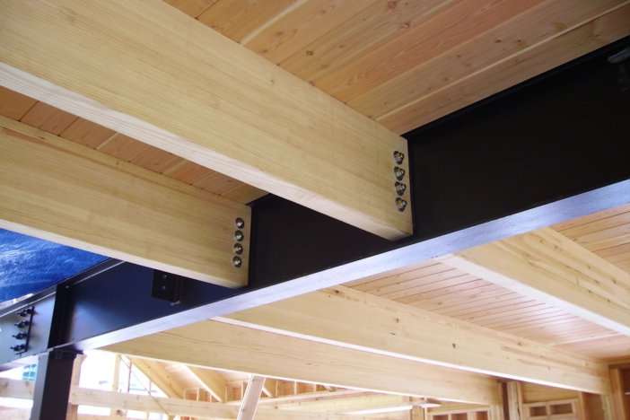 a wooden ceiling with a metal beam attached to it.