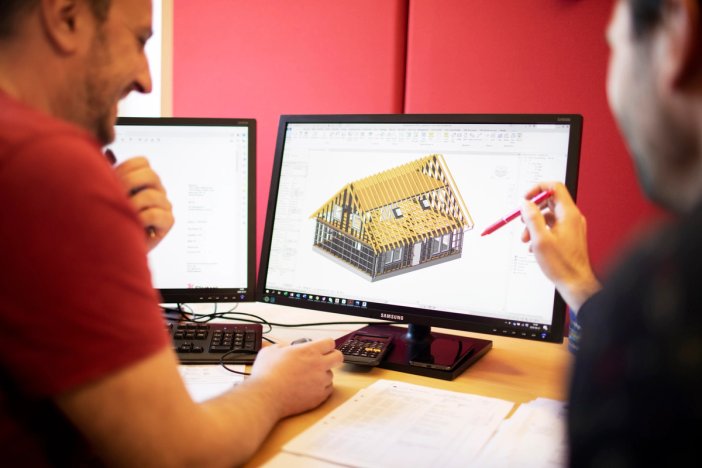 two men are sitting at a desk looking at a computer screen.