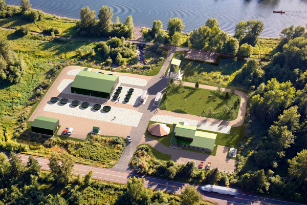Aerial view of a modern facility with green buildings and circular tanks next to a river, surrounded by trees.