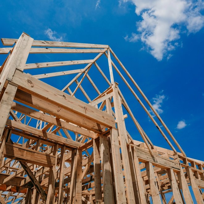 a wooden house is being built with a blue sky in the background .