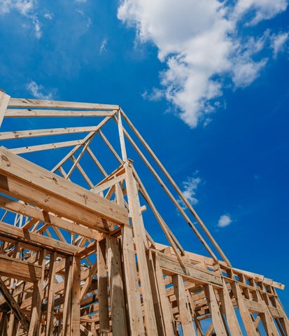 a wooden house is being built with a blue sky in the background .