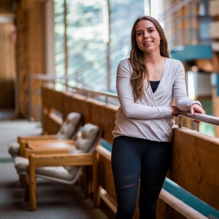 a woman is leaning on a railing in a hallway.