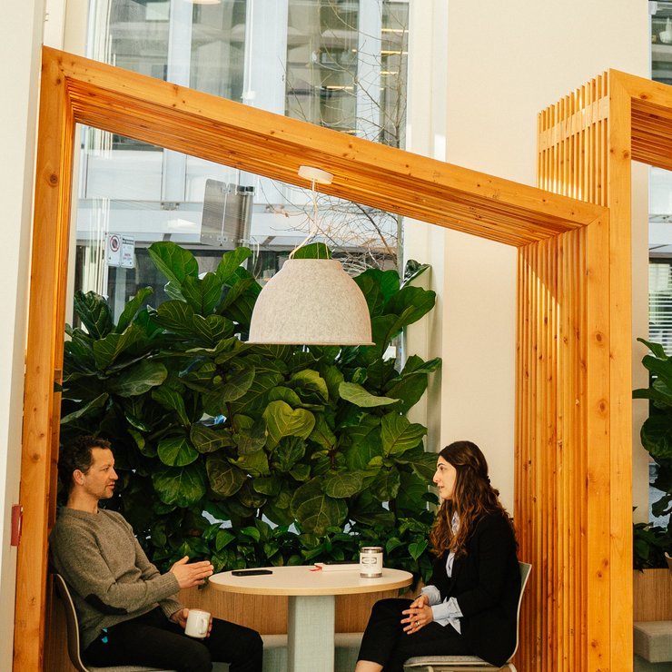a man and a woman are sitting at tables in a room with plants .
