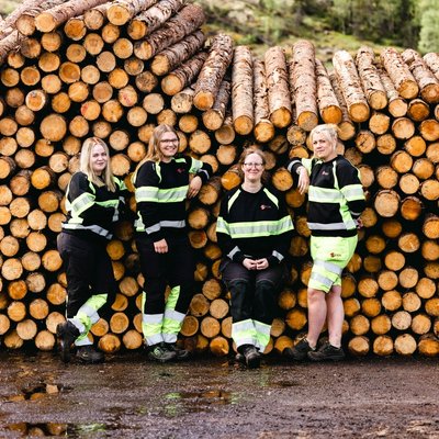 a group of women are posing for a picture in front of a pile of logs .