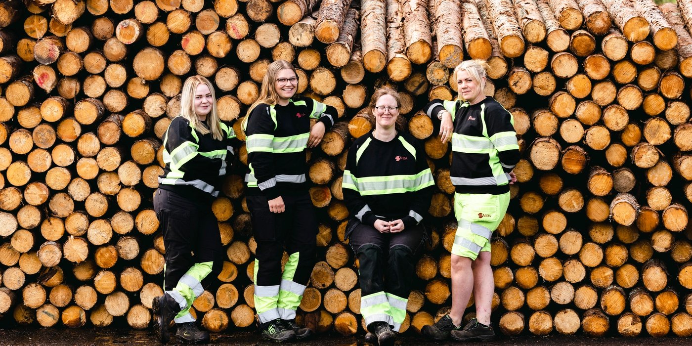 a group of women are posing for a picture in front of a pile of logs .