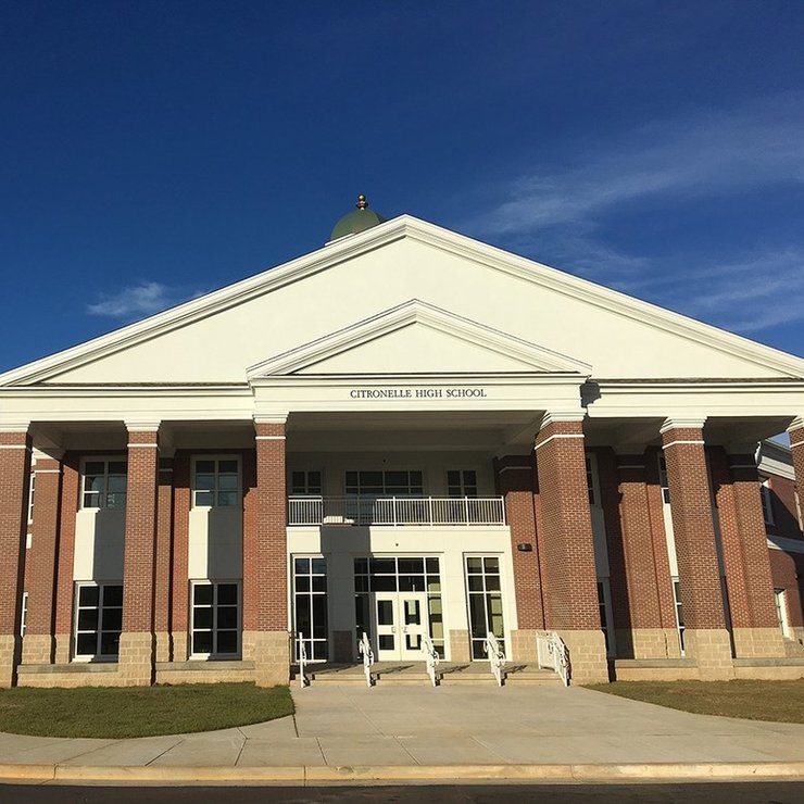 the front of a large brick school building with a blue sky in the background .