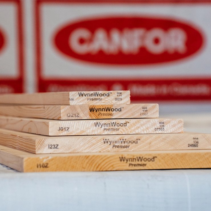 Five WynnWood Premier wooden boards laid on a surface, with blurred Canfor logos in the background.