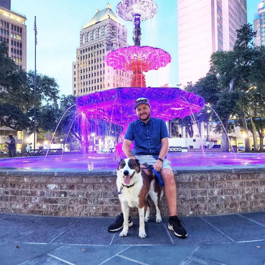 a man and his dog are sitting in front of a purple fountain .