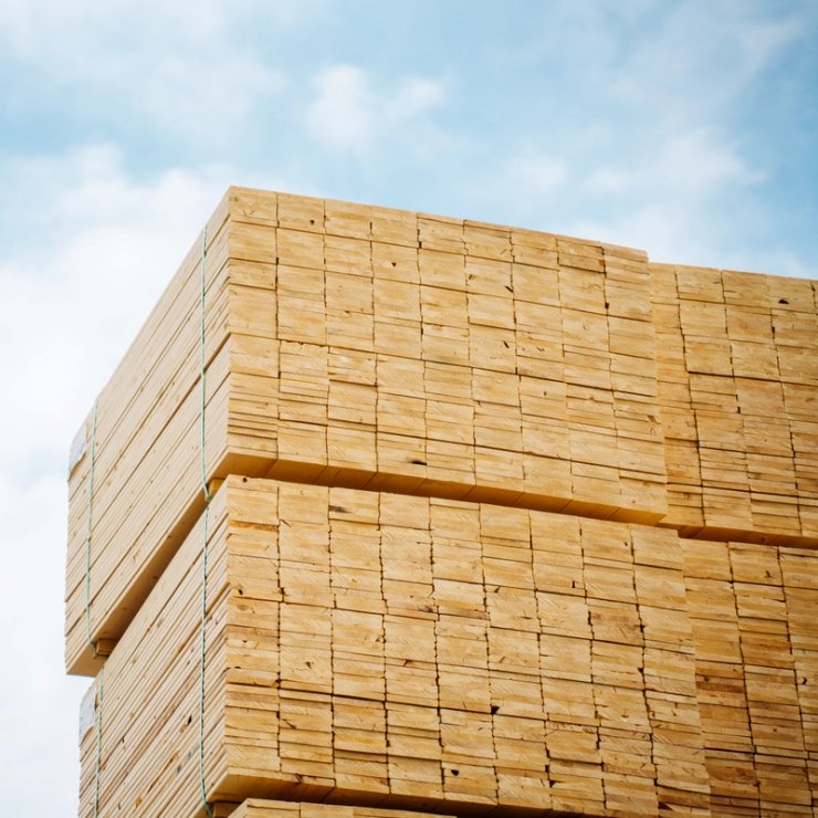 Stacks of light-colored lumber against a cloudy sky.