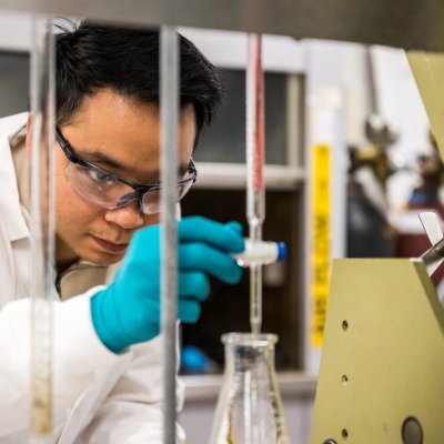 a man in a lab coat and gloves is working in a lab .