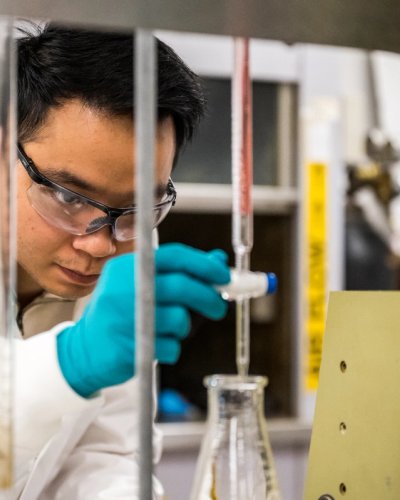 a man in a lab coat and gloves is working in a lab .