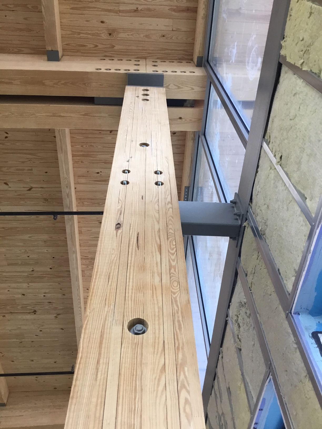 a wooden beam with holes in it is attached to a window.