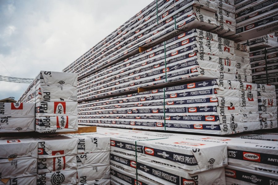 Bundles of "POWER PRODUCTS" lumber from Canfor, wrapped and stacked outdoors.