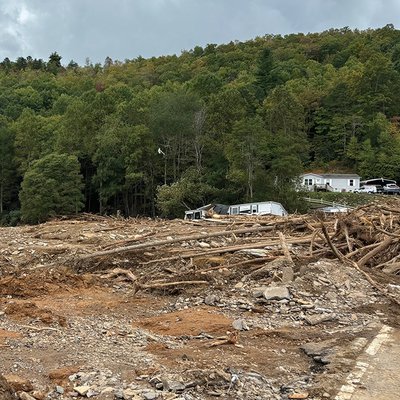 there is a lot of debris in the middle of a field with a house in the background .