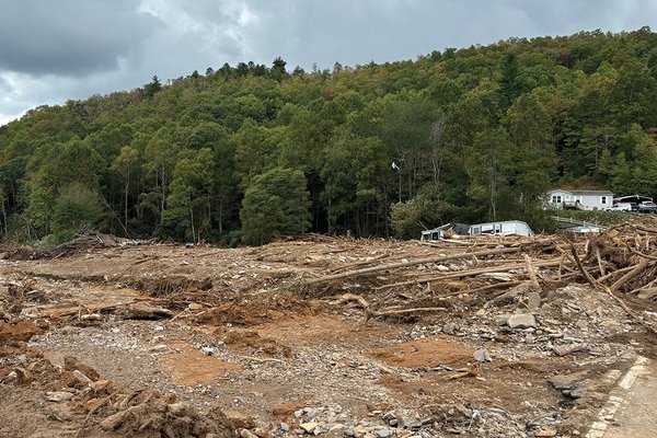 there is a lot of debris in the middle of a field with a house in the background .