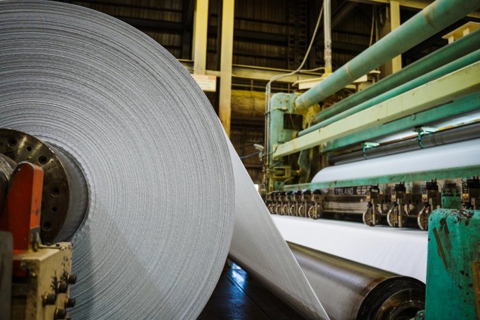 a large roll of paper is being rolled on a machine in a factory .