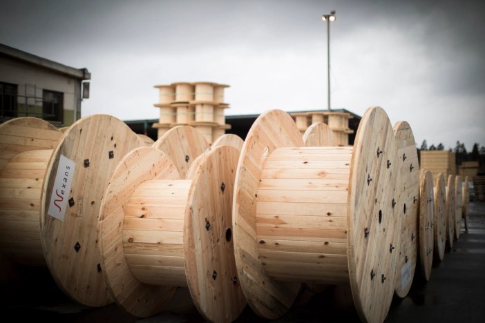 a bunch of wooden spools are stacked on top of each other in a warehouse .