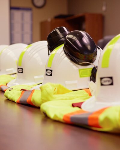a row of hard hats and safety vests are lined up on a table.