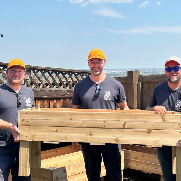 three men are standing next to each other holding a wooden planter .