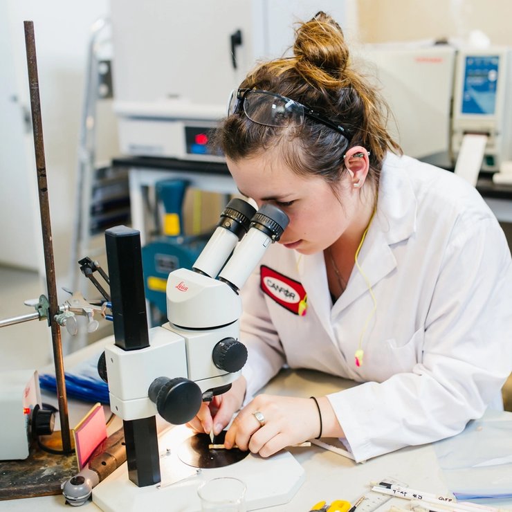 a woman is looking through a microscope in a lab .